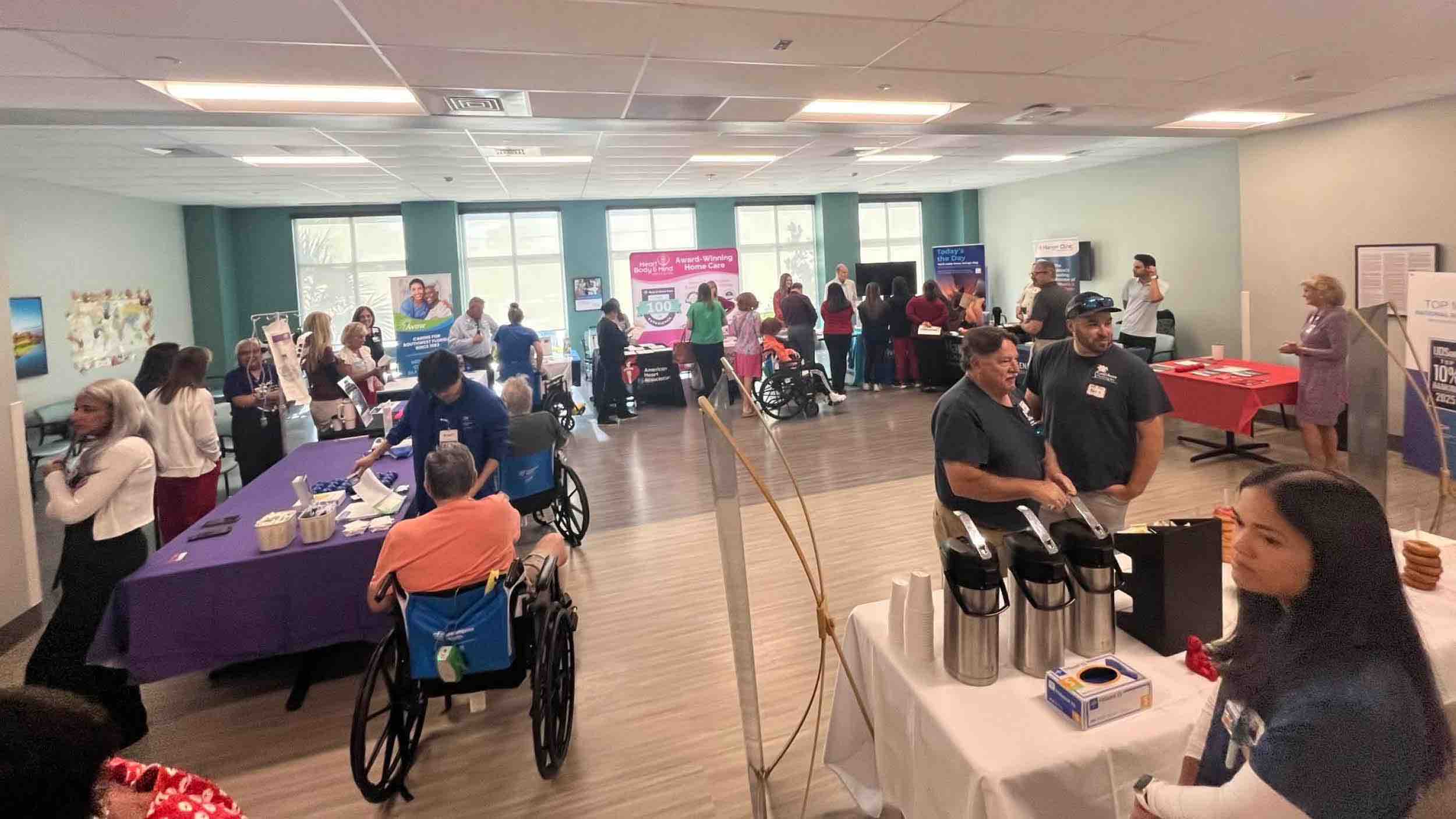 Large indoor stroke awareness event with multiple informational booths, healthcare staff, and attendees including wheelchair users, highlighting stroke rehabilitation services and community education resources.