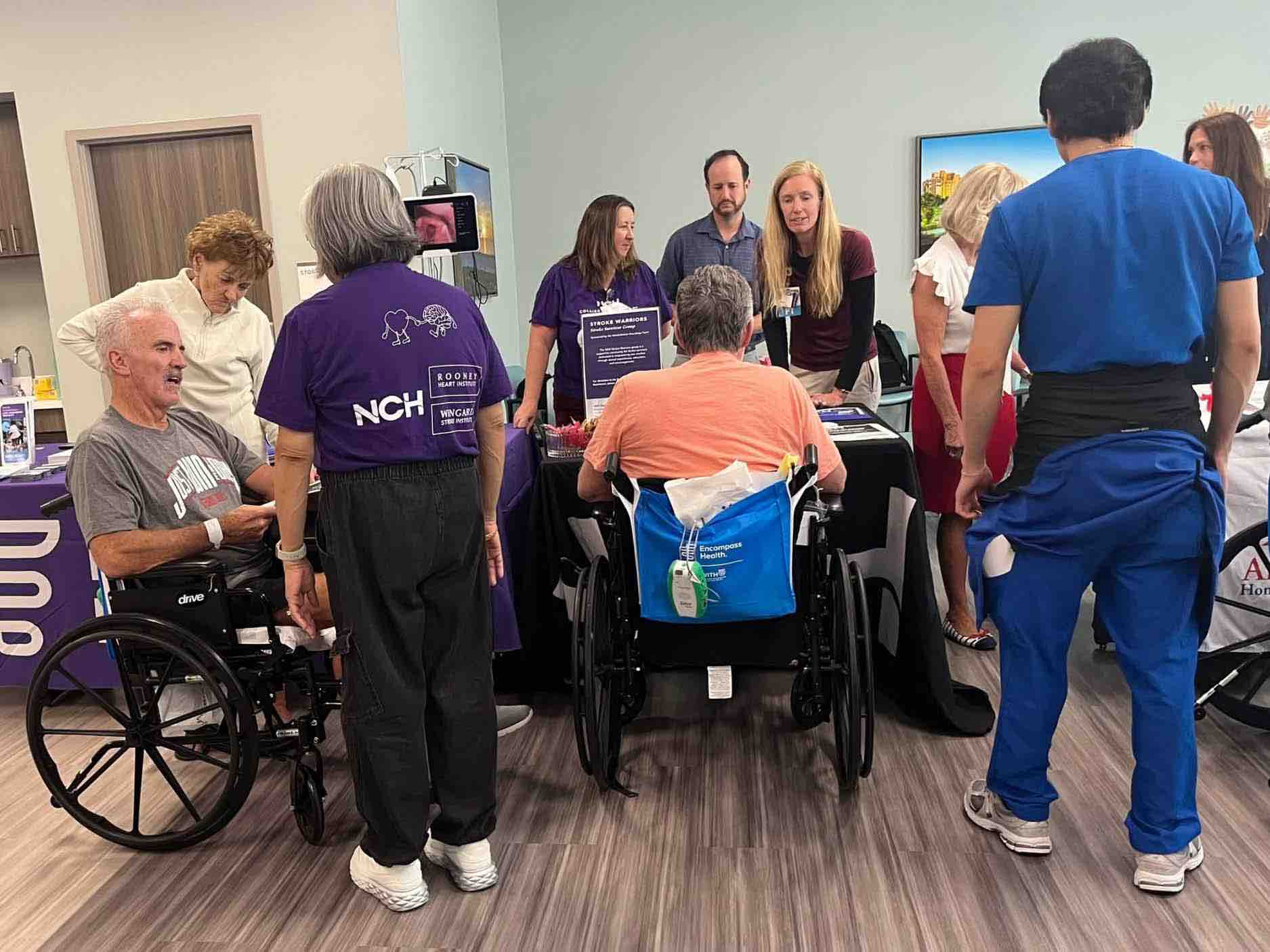Stroke survivors and healthcare professionals gather around informational booths, including individuals in wheelchairs, promoting stroke recovery, rehabilitation resources, and community support programs.