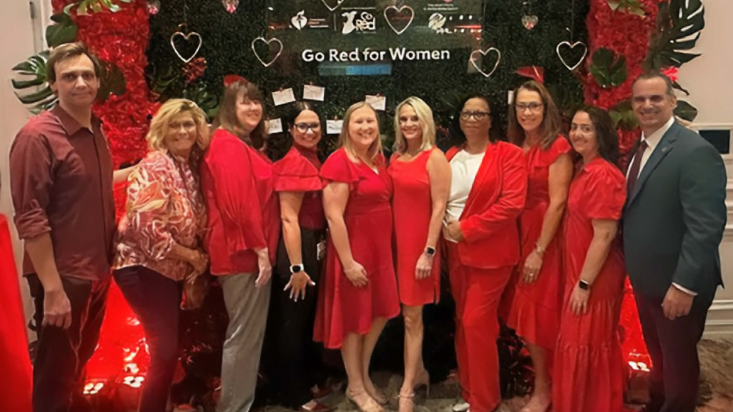 Group photo at Palm Beach Go Red event featuring participants dressed in red standing before a floral backdrop, promoting heart health awareness and supporting stroke survivor advocacy.
