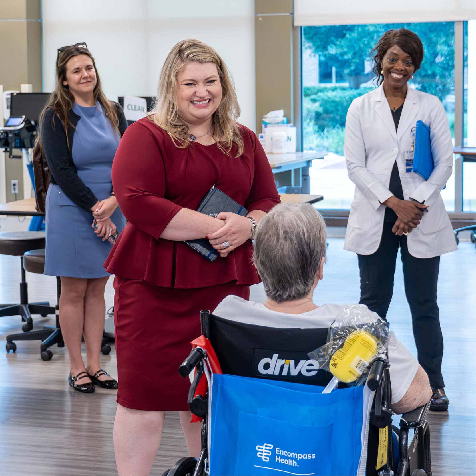 Visitor speaks with a patient during a tour of an inpatient rehabilitation hospital, learning about recovery experiences, patient care and rehabilitation services.