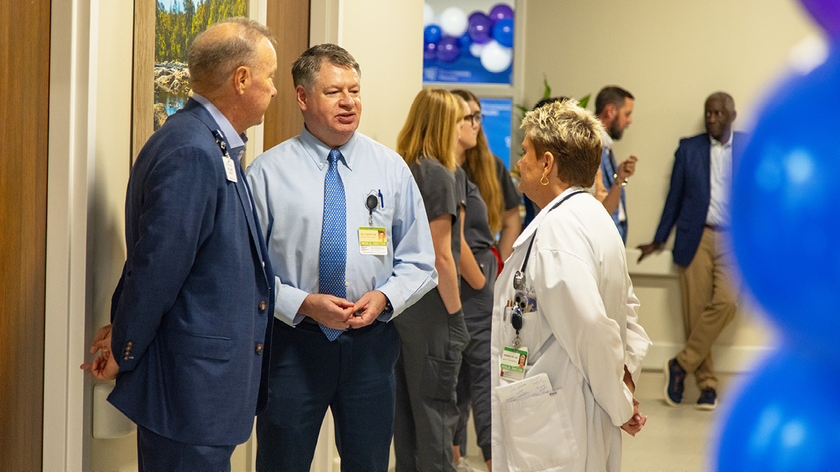 Healthcare professionals and staff members gather and talk in a hospital hallway decorated for a facility event.