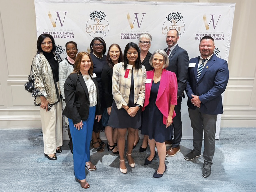 Group photo of award recipients and colleagues posing in front of a Most Influential Business Women event backdrop.