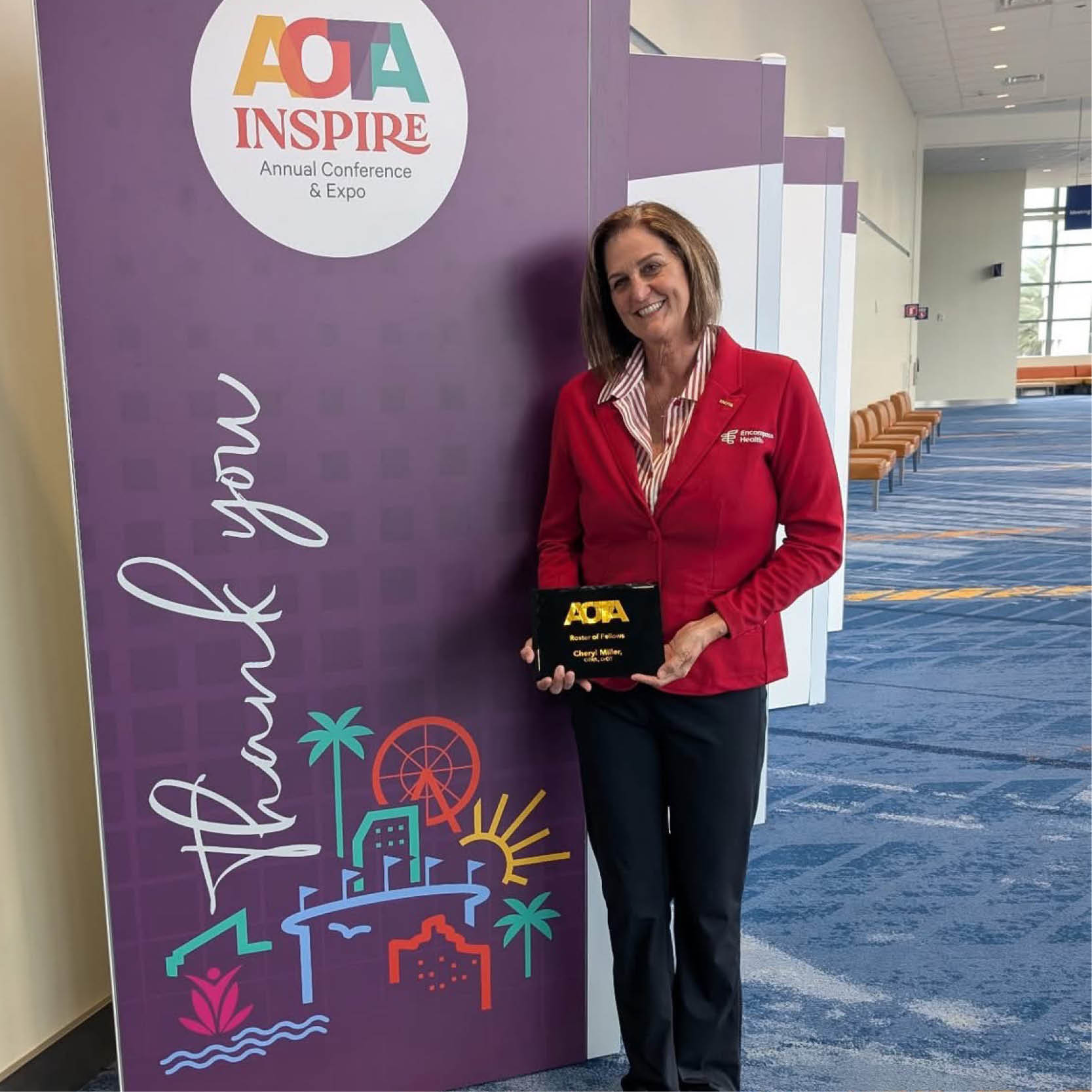 Cheryl Miller stands at the AOTA INSPIRE Annual Conference holding an AOTA Fellowship award plaque, honoring leadership in occupational therapy and rehabilitation care.