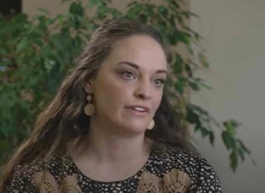 Angie, a spinal cord injury patient, sitting indoors during an interview with a plant in the background.