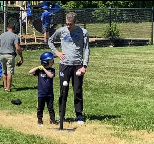 Matt coaching son to hit tee ball on baseball field