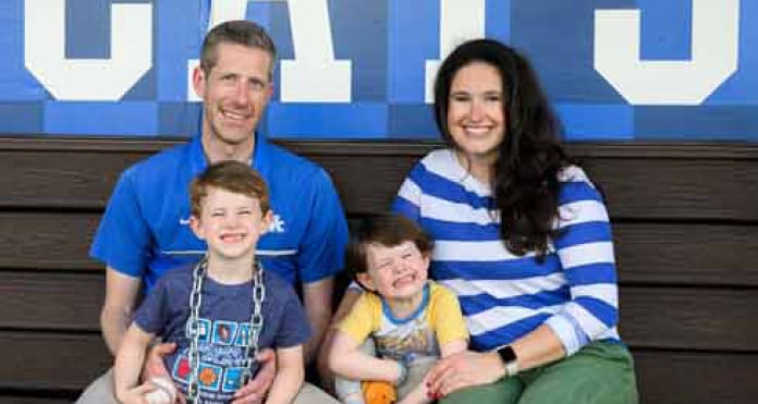 A family sits together on a bench in front of a blue wall with large white lettering, representing a supportive moment during Matt’s stroke recovery.