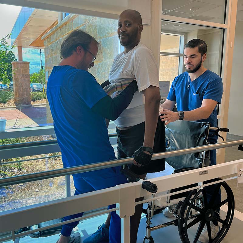 Joe Pearson rising from his wheelchair during physical therapy