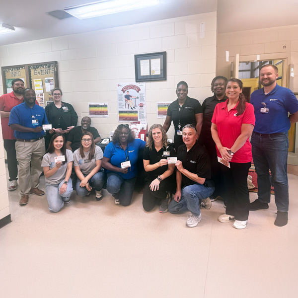 A group of Encompass Health Columbia employees pose together, holding American Heart Association cards that read 