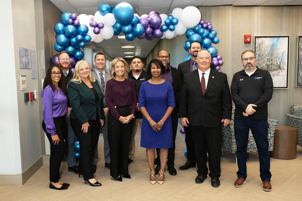 Encompass Health Rehabilitation Hospital of Toledo leadership stands smiling in front of a festive balloon arch with blue, purple, and white balloons.