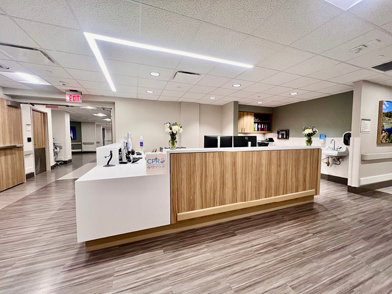 Modern hospital reception area with a wooden desk, computers, and flower arrangements. Bright lighting and a clean atmosphere. Exudes professionalism.
