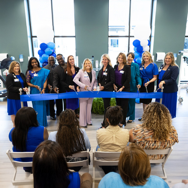 Encompass Health staff holding blue ribbon during Grand opening celebration in hospital lobby