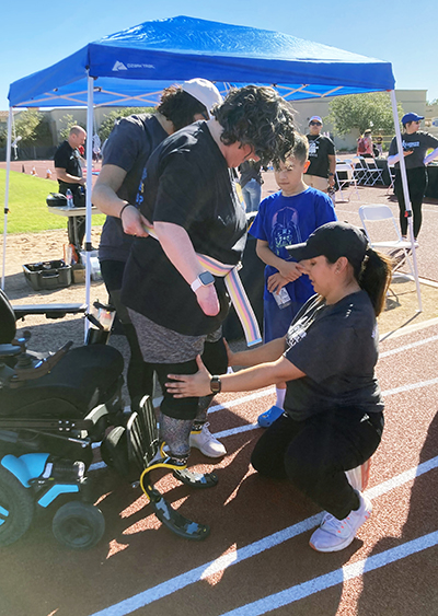 amputee wellness clinic staff helping an attendee stand