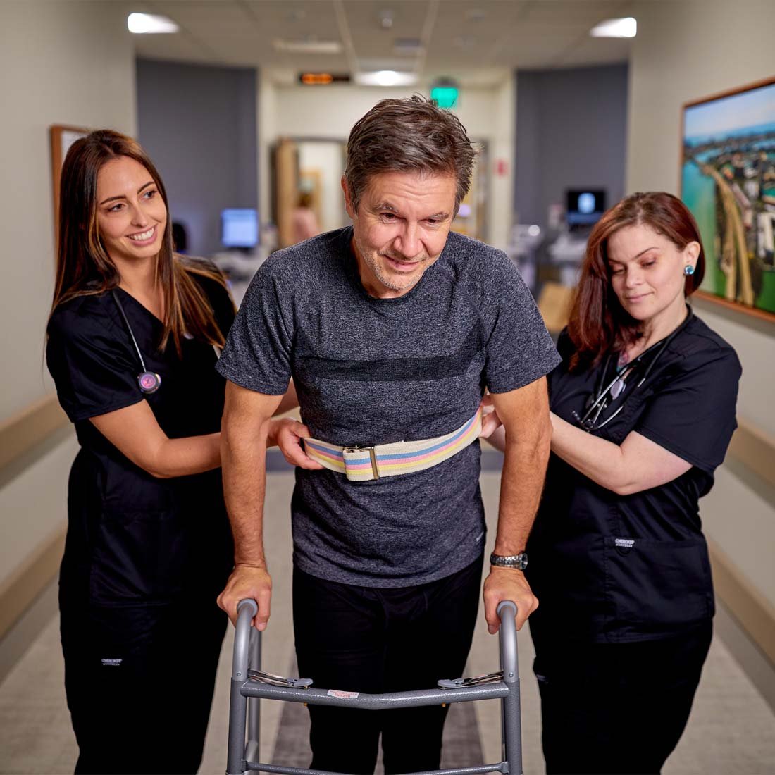 Nurses helping a patient walk while using a walker