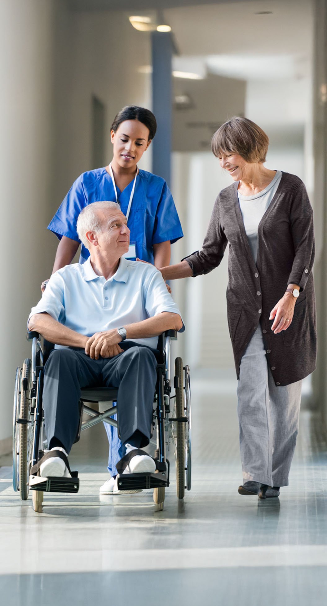 A patient in a wheelchair being pushed by a nurse