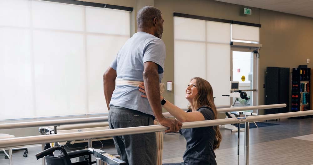 Patient being assisted by a physical therapist on the parallel bars