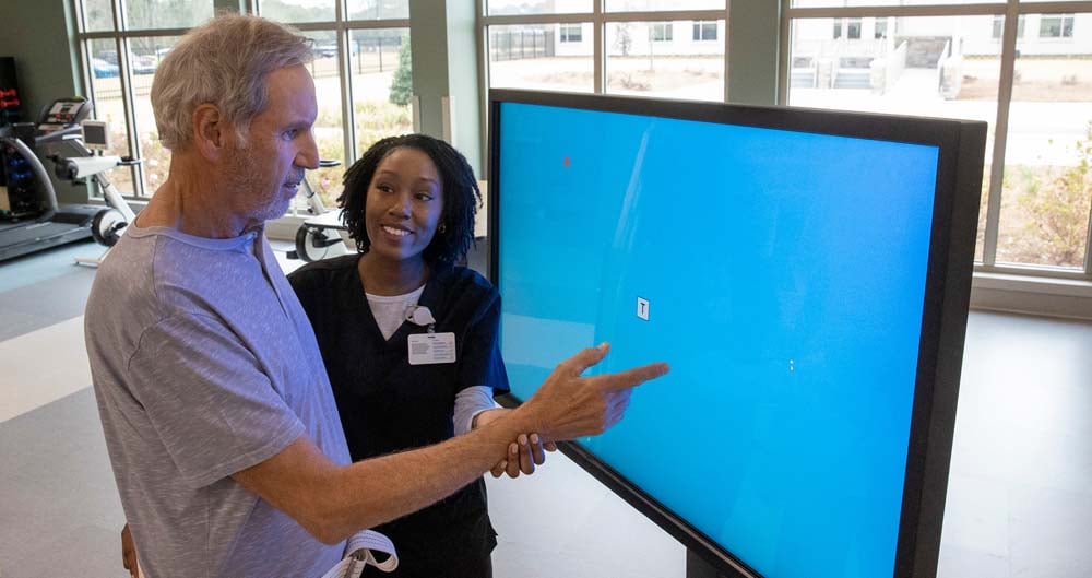 Patient being assisted by a physical therapist with a touch screen