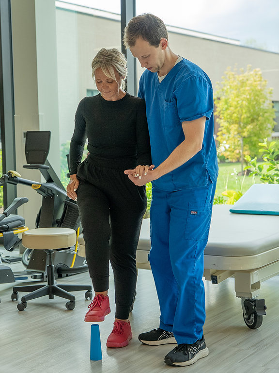 Rehabilitation patient completing a supported step exercise using balance equipment during therapy, demonstrating strength and coordination goals within the Susan Lannon brain injury recovery success story.