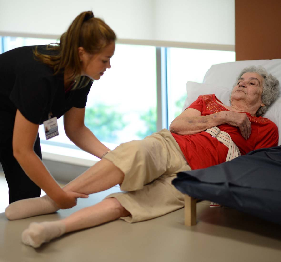 Rehab nurse adjusting a patient's leg