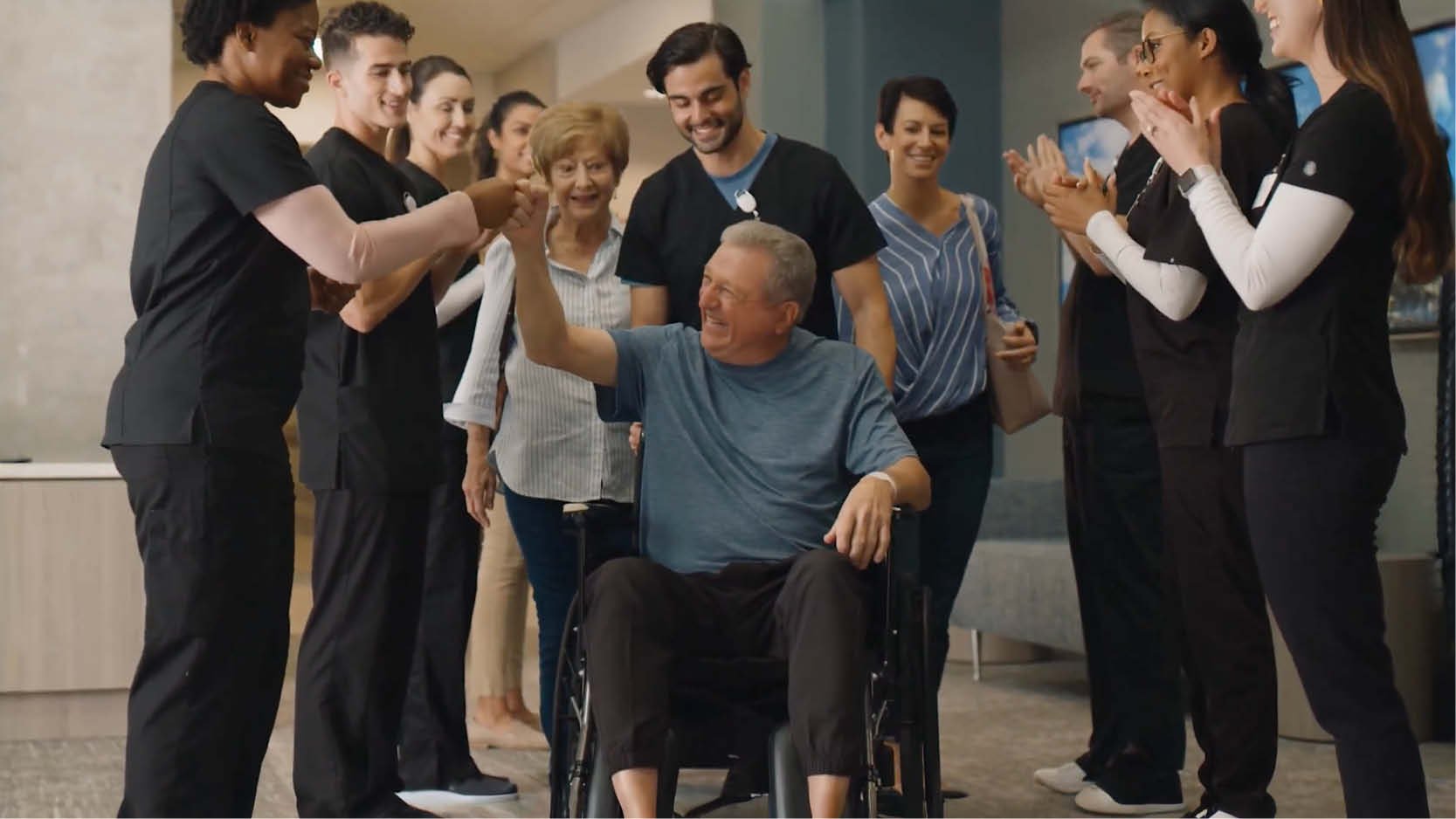 Patient in a wheelchair celebrates rehabilitation progress with a multidisciplinary care team, highlighting recovery milestones, teamwork and patient-centered care.