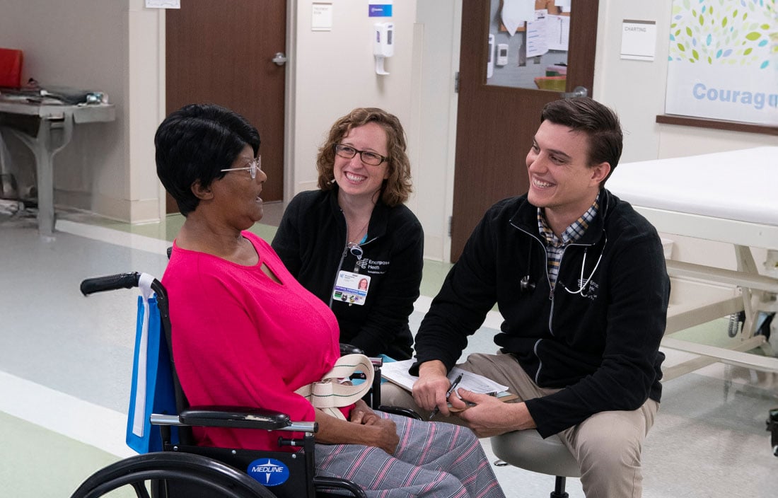 Rehab staff speaking with a patient in a wheelchair