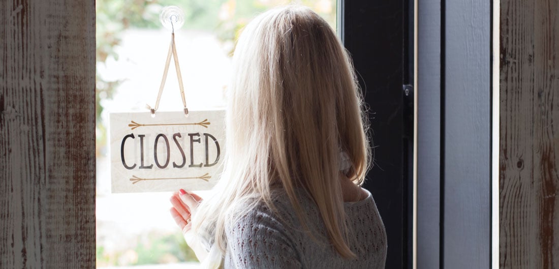 woman flips open closed sign on business door