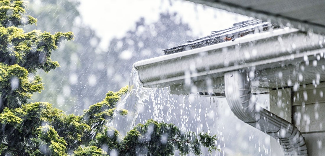 rain pours onto gutters on home