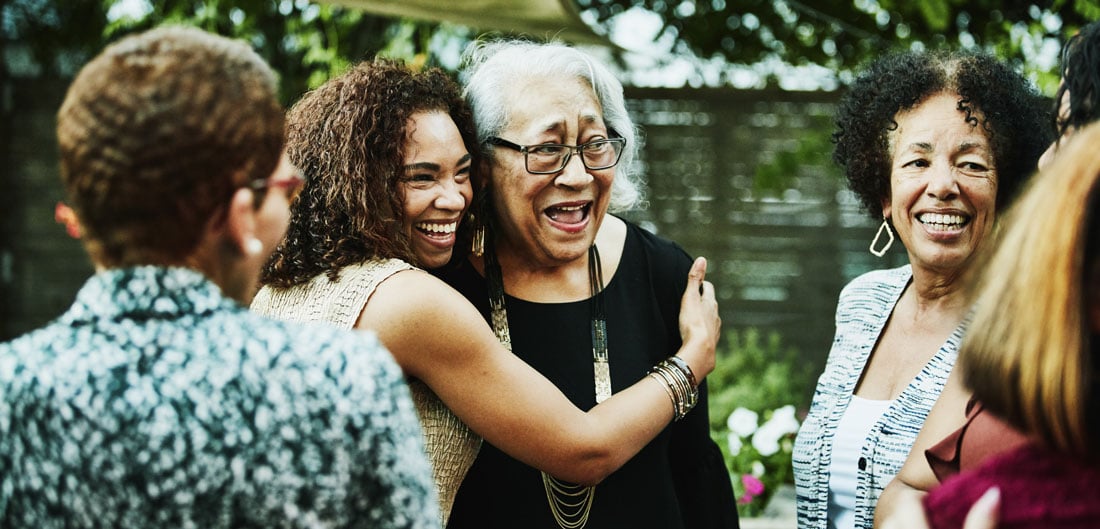 young adult woman hugs senior woman at family gathering