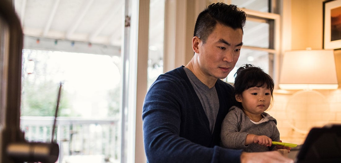 father and toddler sit together at laptop computer