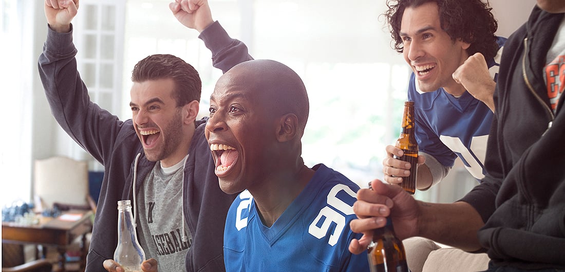 three young men cheer for football in living room