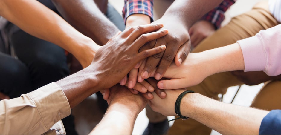 diverse team members put hands together