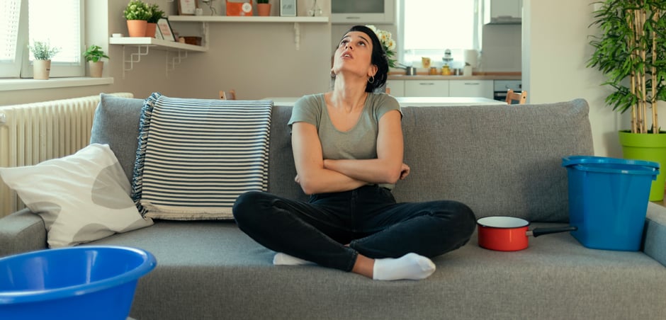 woman looks concerned at leaking roof
