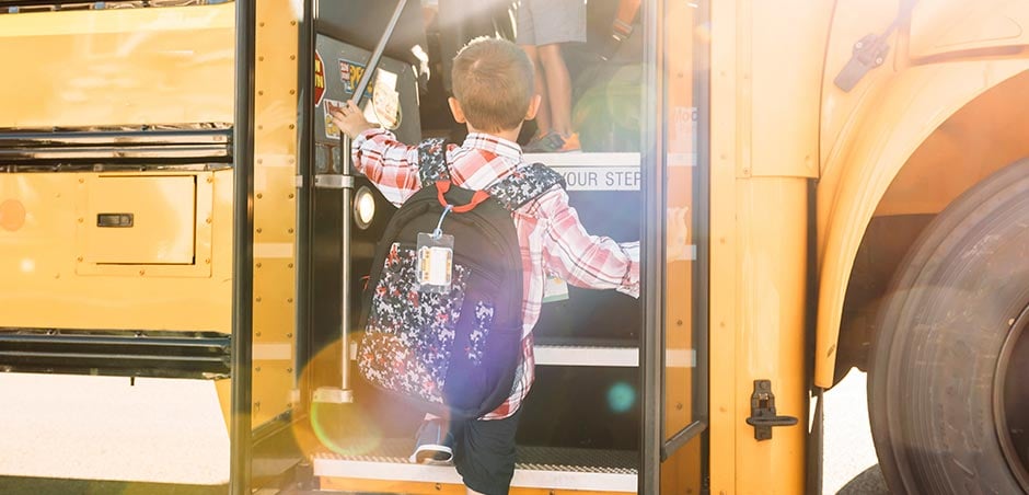young boy boards a school bus