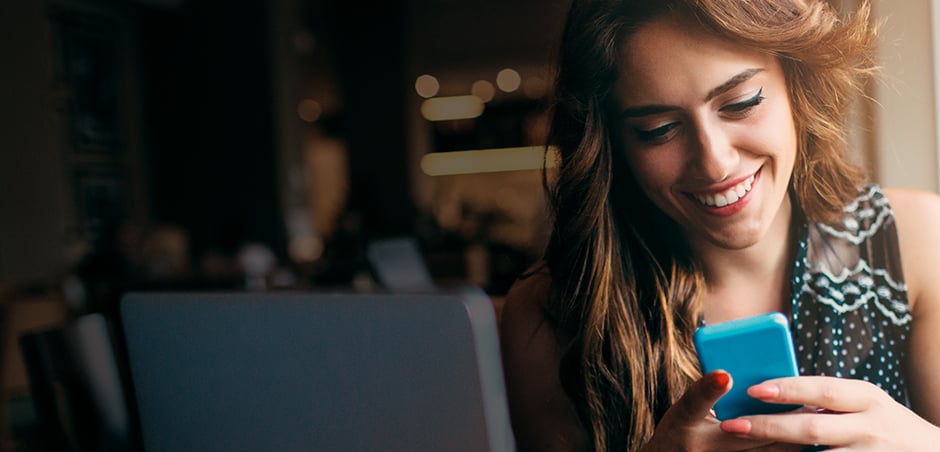 woman smiles while holding smartphone