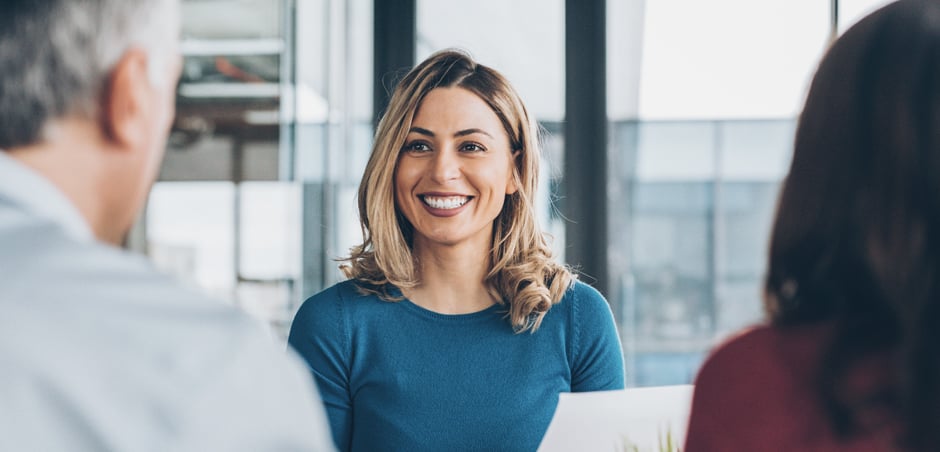 Smiling woman in blue shirt sitting across from a man and woman