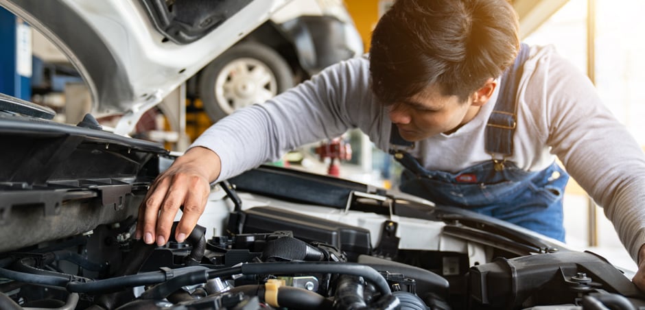 mechanic opens hood of car and examines engine