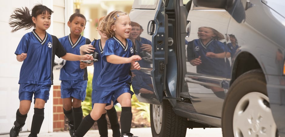 three children in soccer uniforms open door to enter minivan