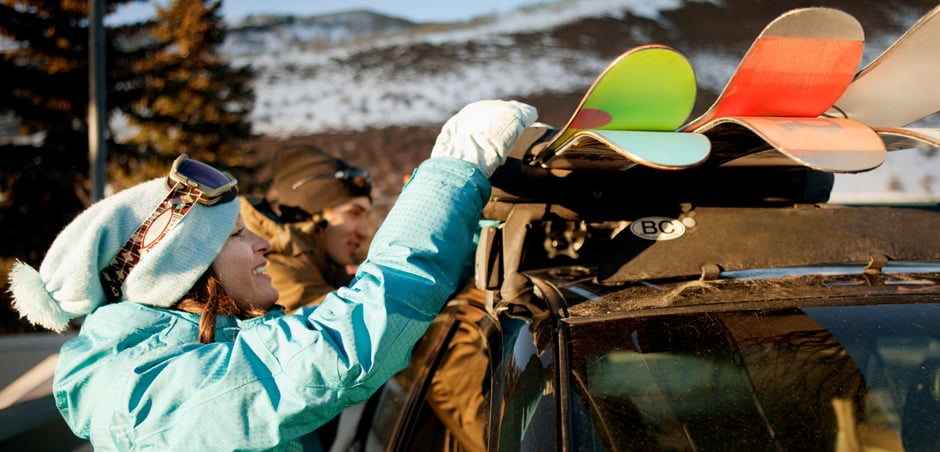 couple puts snowboards on top of car