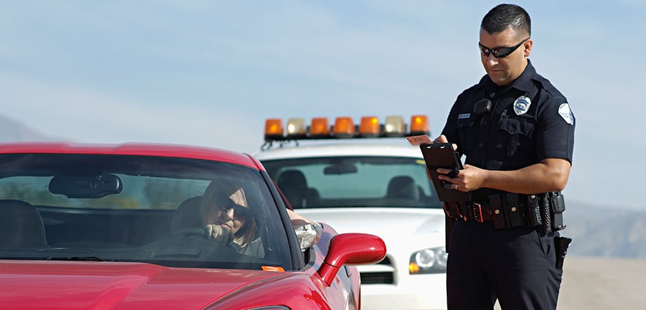 police officer standing to the right of a red car