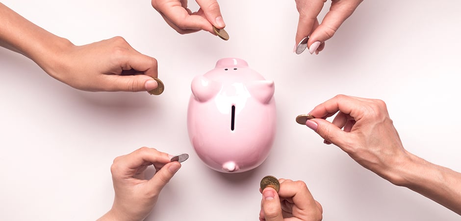 six hands put money into a piggy bank