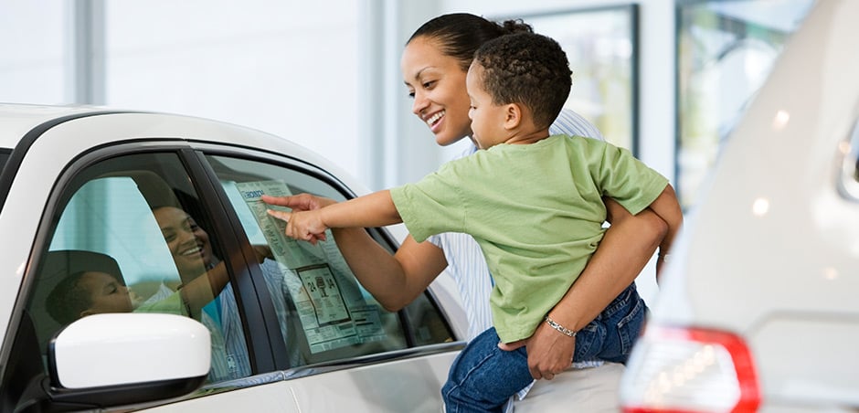 woman holding child next to car
