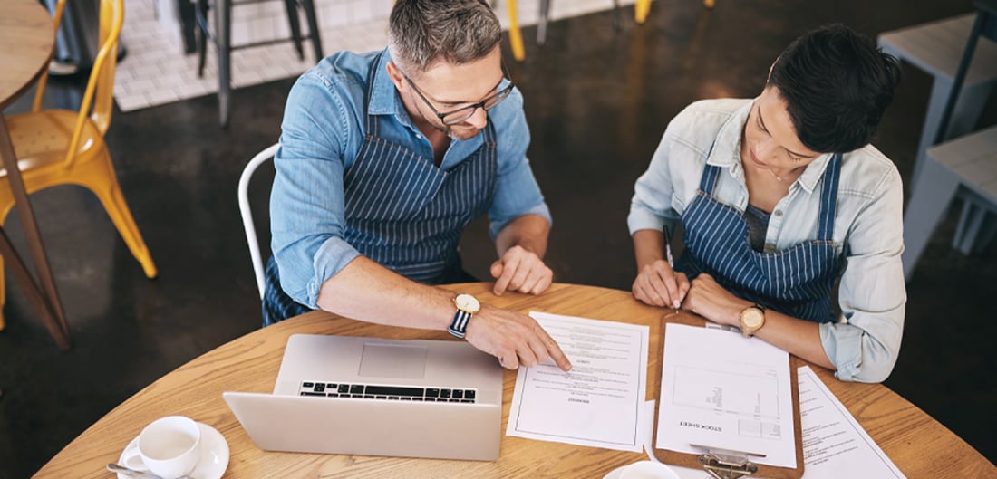 two people sitting at a table looking over some documents