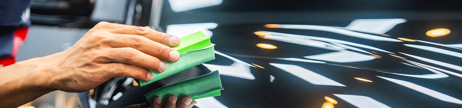 hand with a sponge washing car