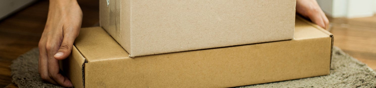 hands picking up stacked packages on the ground