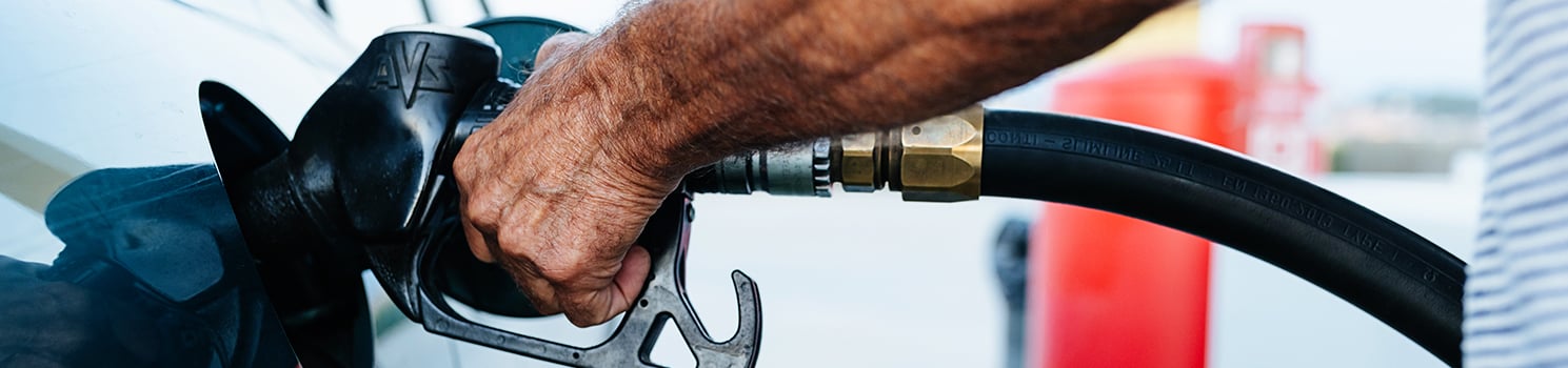 person inserting gas pump nozzle into vehicle