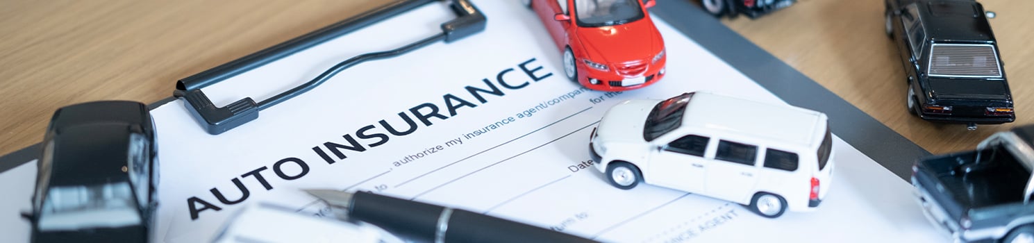 paper with auto insurance on a desk with toy cars around