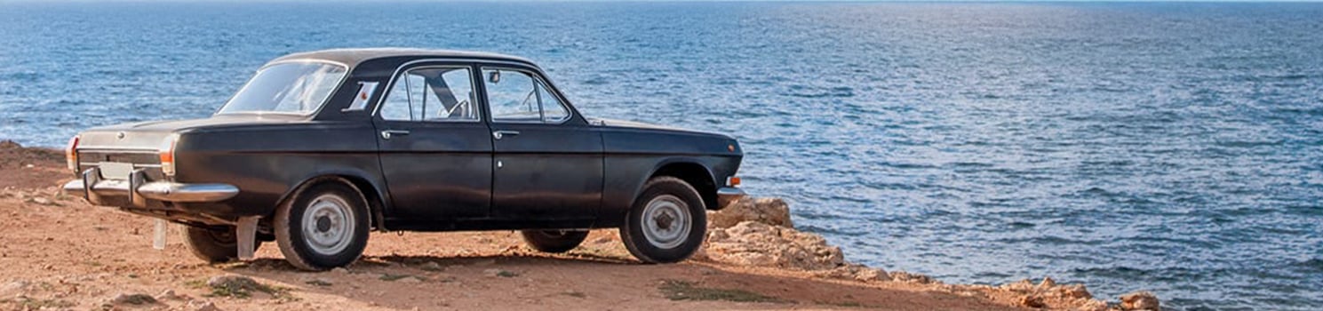 a car parked on the edge of a cliff overlooking water