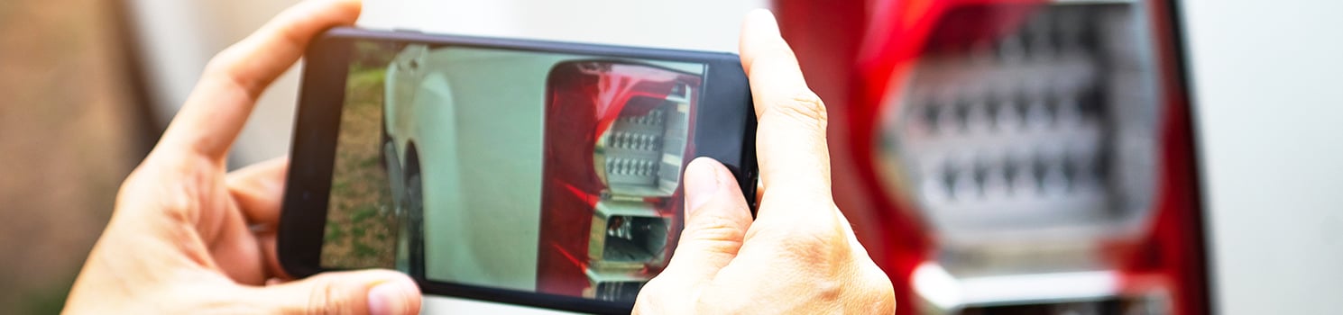 person taking photo of car with smartphone