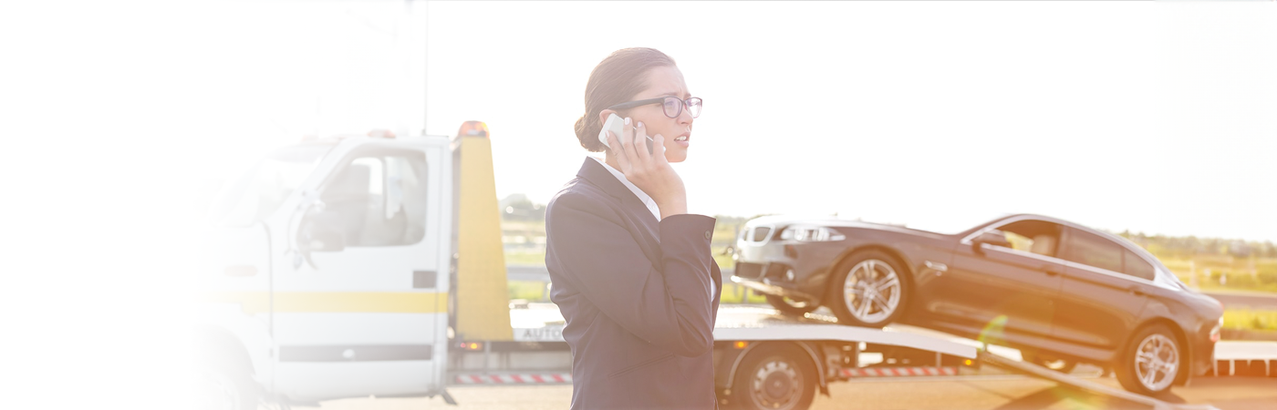 car being towed with business woman on phone