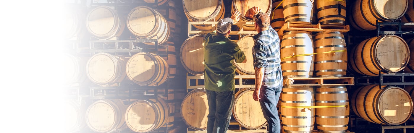 Two men inspecting wooden barrels