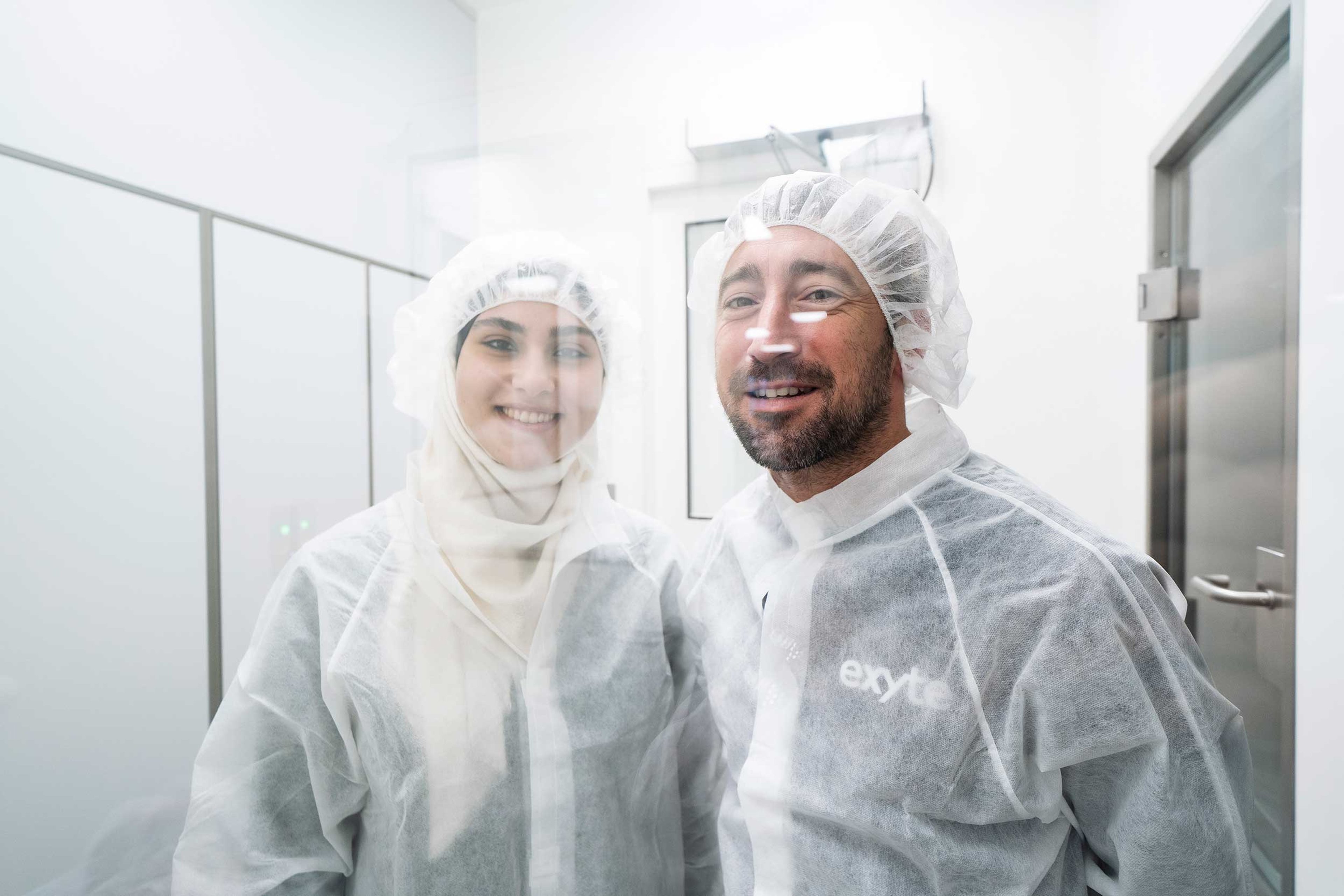 Two people in cleanroom bunnysuits